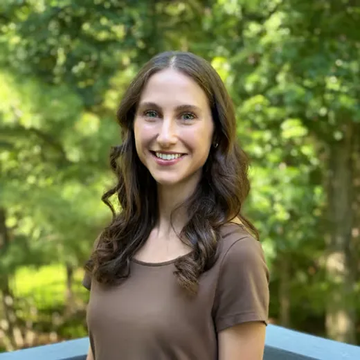 Sarah Vinchesi, Licensed Mental Health Counselor, smiling outdoors among green trees